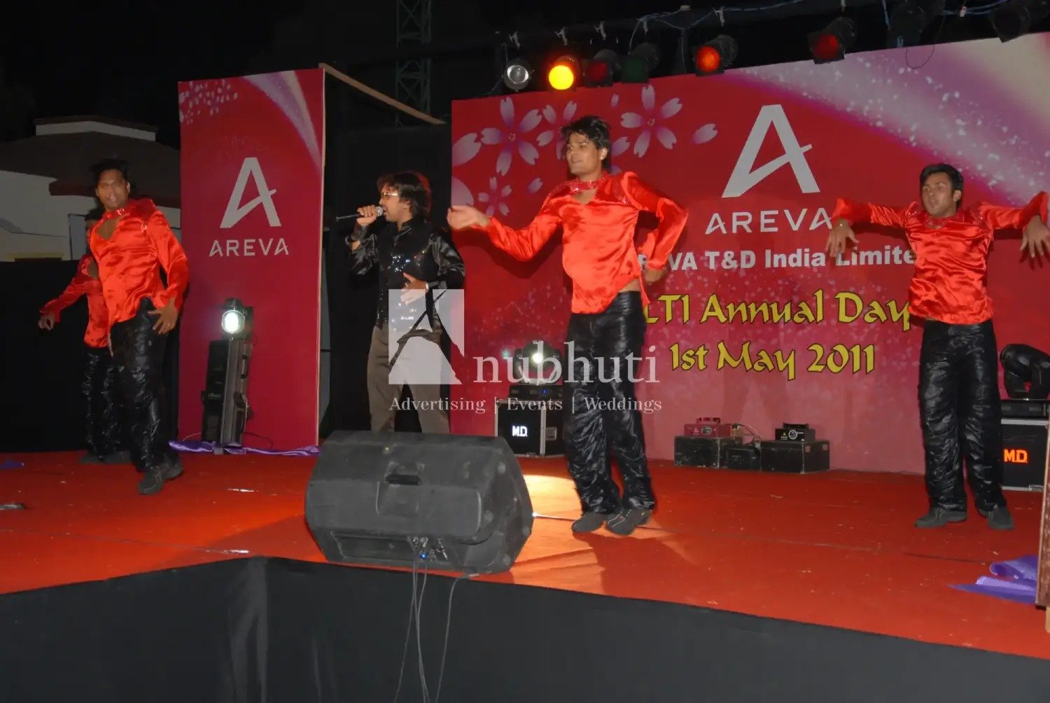 Man and woman speaking on stage at night with blue lighting
